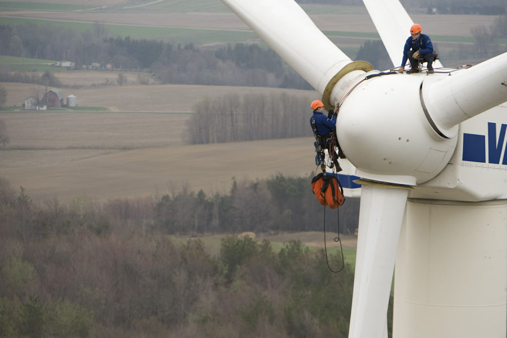 Two rope access technicians inspect a wind turbine.